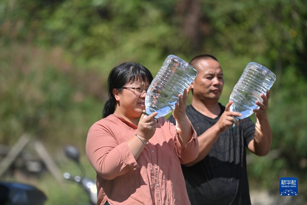 楊寧（左）在查看村民剛剛采集的水樣，為山泉水引水工程做準備（10月8日攝）。新華社記者 黃孝邦 攝